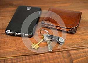 Leather purse, phone pouch and keys on a wooden table background