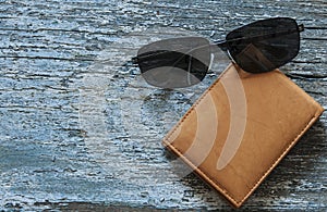 leather purse with sunglasses lying on a wooden table