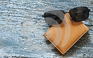 leather purse with sunglasses lying on a wooden table