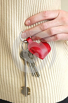 Leather red heart key trinket as a valentines day gift closeup photo on white sweater background