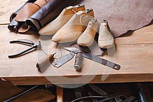 Leather in rolls, cobbler tools and shoe lasts in workshop. Leather craft tools.
