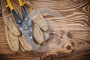 Leather safety gloves tin snips on vintage wooden board construc