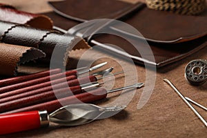 Leather samples and tools on brown table, closeup