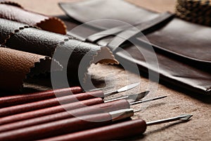 Leather samples and tools on brown table, closeup