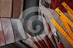 Leather samples and tools on brown table, flat lay