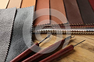 Leather samples and tools on wooden table, closeup