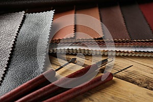 Leather samples and tools on wooden table, closeup