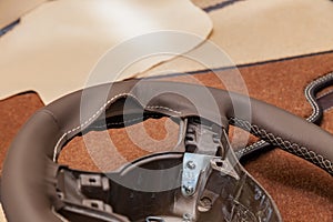 Leather steering wheel brown color in the process of stitching with a bright contrast seam and white central point on the top in