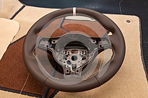 Leather steering wheel brown color in the process of stitching with a bright contrast seam and white central point on the top in