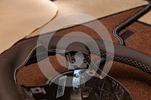 Leather steering wheel brown color in the process of stitching with a bright contrast seam and white central point on the top in