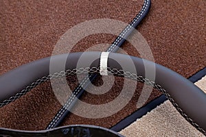 Leather steering wheel brown color in the process of stitching with a bright contrast seam and white central point on the top in