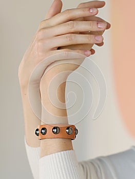 Piel densamente marrón pulsera sobre el una mujer mano detallado en blanco muro 