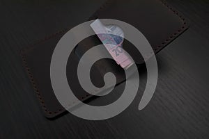 Leather wallet with money on a dark background