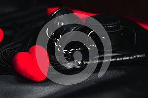 Leather whip and handcuffs for BDSM sex with red hearts as a symbol of Valentine`s day