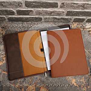 Leather Zipper Portfolio. Concept shot, top view, flap portfolio in brown colors and leather pen. Custom background flap portfolio