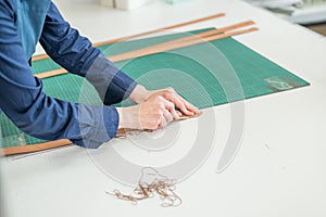 Leatherworker measuring and cutting leather in workshop.