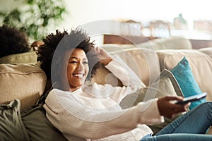 On leave until further notice. Shot of a young woman relaxing on the sofa at home and watching tv.