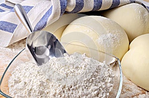 Leavened pizza dough with flour and scoop, closeup.