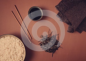Leaves and chopped Nori shavings, with a cup of boiled rice, top view, on a brown background, selective focus, no people