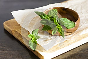 Leaves of fresh mint in a wooden bowl on the kitchen table