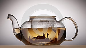 Leaves of green tea are brewed in teapot, white background