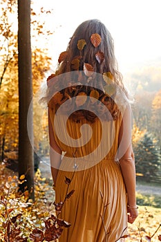 Leaves in the hair of a woman walking on a warm autumn day in the forest