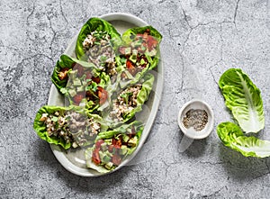 Leaves of mini roman salad stuffed with tuna, egg, tomato, avocado on a gray background, top view. Delicious appetizer, tapas,