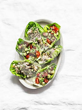 Leaves of mini roman salad stuffed with tuna, egg, tomato, avocado on a light background, top view. Delicious appetizer, tapas,