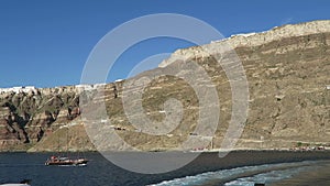 Leaving the Harbor Ormos Athinios at Santorini Isle Greece. in background buses driving up the caldera wall towards Fira.