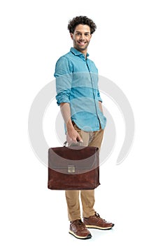 lebanese man holding suitcase and smiling while standing with hand in pocket