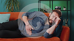Lebanese man lying on sofa feeling sudden strong abdominal stomach ache, gastritis problem, diarrhea