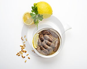 Lebanese starters of Makanek meat marinated, sausages fried in a metal pan isolated on white