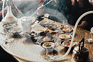 Lebanon cuisine served in restaurant. A young company of people is smoking a hookah and communicating in an oriental restaurant. T