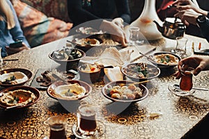 Lebanon cuisine served in restaurant. A young company of people is smoking a hookah and communicating in an oriental restaurant. T