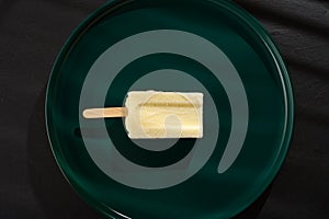 a leben or yoghourt flavor popsicle in the shade of a window