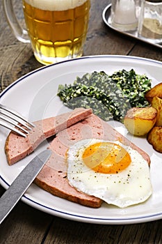 LeberkÃ¤se with spinach, potatoes and fried egg photo
