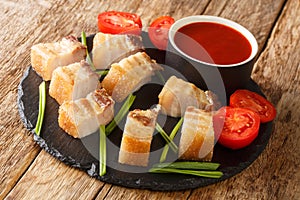 Lechon kawali crispy pan-fried pork belly, is a tasty Filippino food closeup in the slate dish. Horizontal