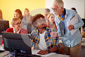 Lecturer in computer class assisting student on university