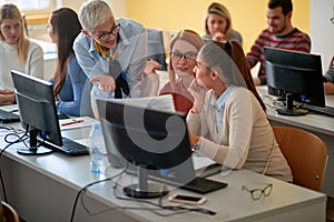 Lecturer with girl students working in computer class on university campus