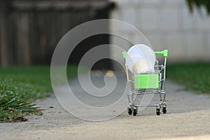LED bulb in a mini shopping basket in the grass as a concept for saving electricity, new ideas