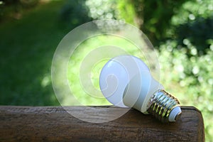 LED bulb on the wooden table and lighting of sub lay with green nature background for eco saving