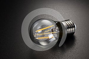 LED filament light bulb on black background