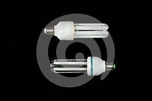 Led and fluorescent energy saving lamps on black isolated background. on the glass