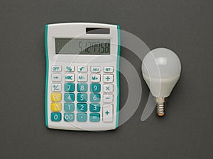 An LED lamp and a classic calculator on a gray background. The concept of energy saving