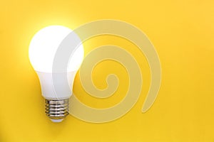 LED light bulb on yellow background, concept of ideas, creativity, innovation or saving energy, copy space, top view, flat lay