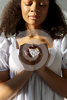 Led lights in hands of young peaceful grateful thankful african american woman making heart sign