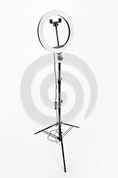 LED ring lamp on a high tripod. White background