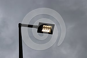 LED street lamp post glowing on dark cloudy sky background