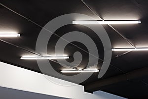 Led tube lights on black office ceiling. Minimal loft design