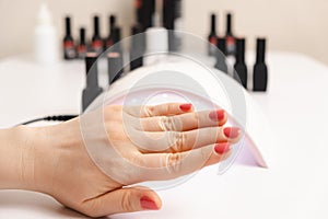 Led uv lamp for drying gel polish and hand with pink coating. Manicure, spa salon